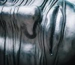 Close-up view of a textured metallic sculpture emphasizing patterns and reflections.